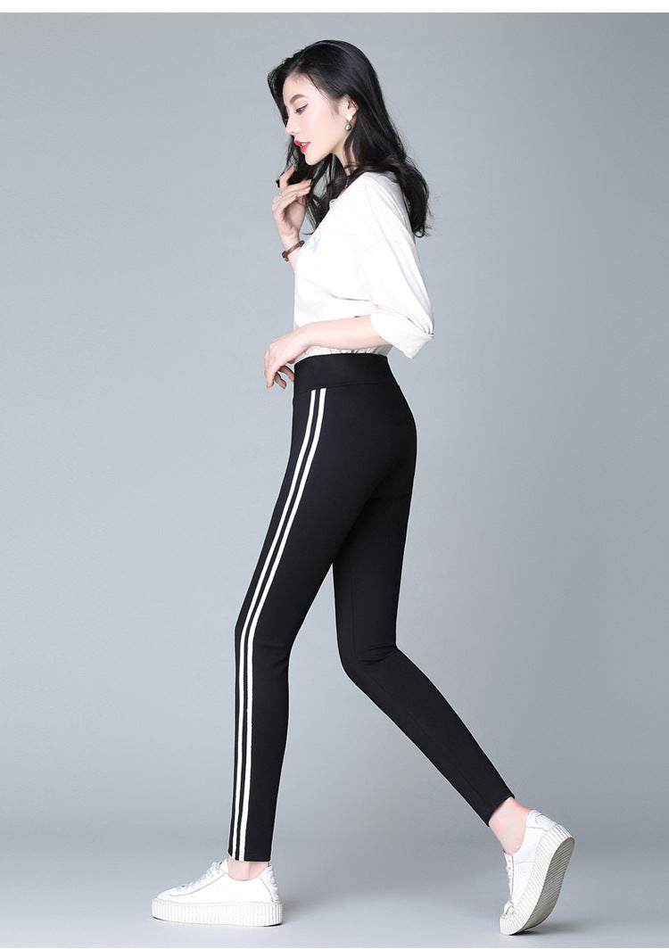 Black pants with two white side stripes, side profile, tapered ankle