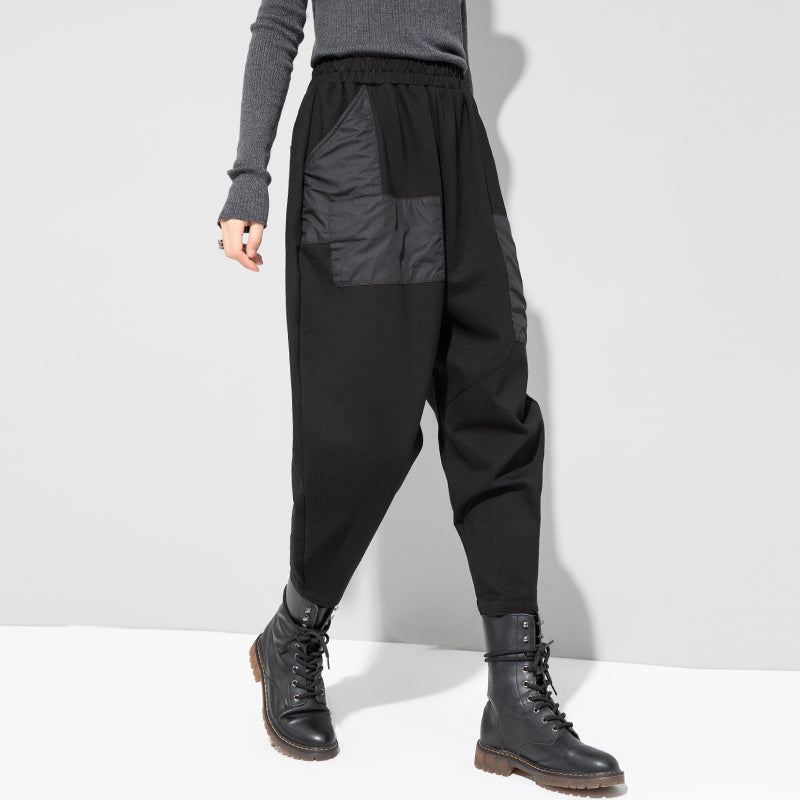 Women's black cropped pants with pleated front, side patch pockets, and elastic waist