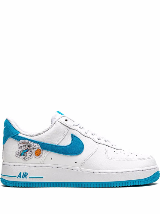 White low-top sneakers with blue swoosh, 'AIR' sole detail and Space Jam graphic