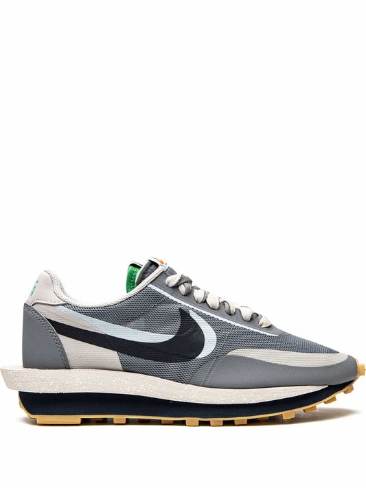 Grey and white low-top sneaker with black swoosh, green heel tab, and textured sole