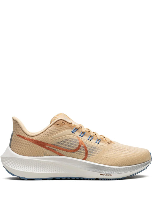 Tan Nike running shoe with red swoosh, blue laces, and white foam sole