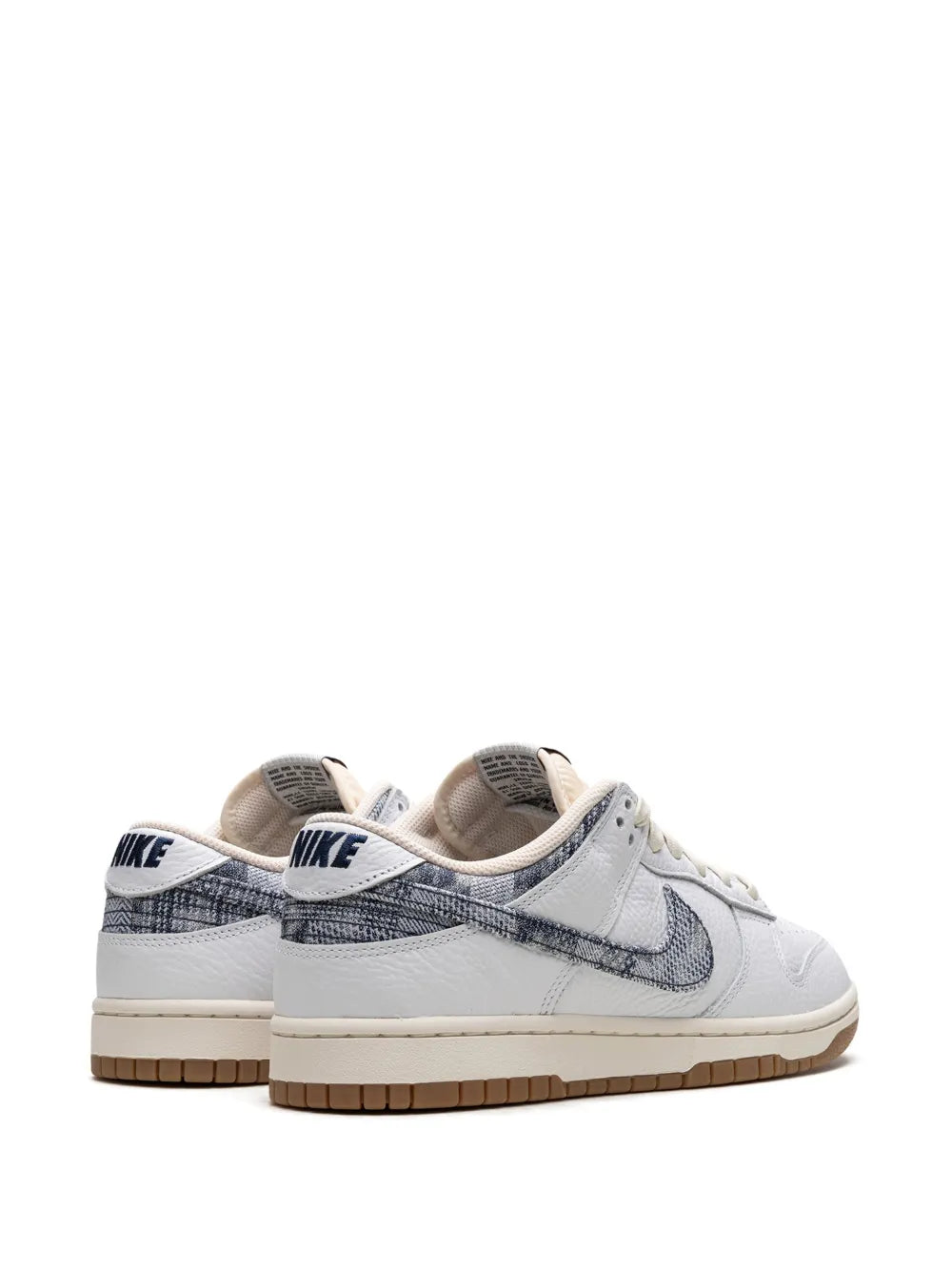 Pair of white low-top sneakers with navy swoosh, Nike branding on heel and tongue