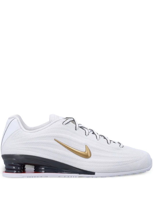 White lace-up trainers with gold swoosh and dark outsole with air pods