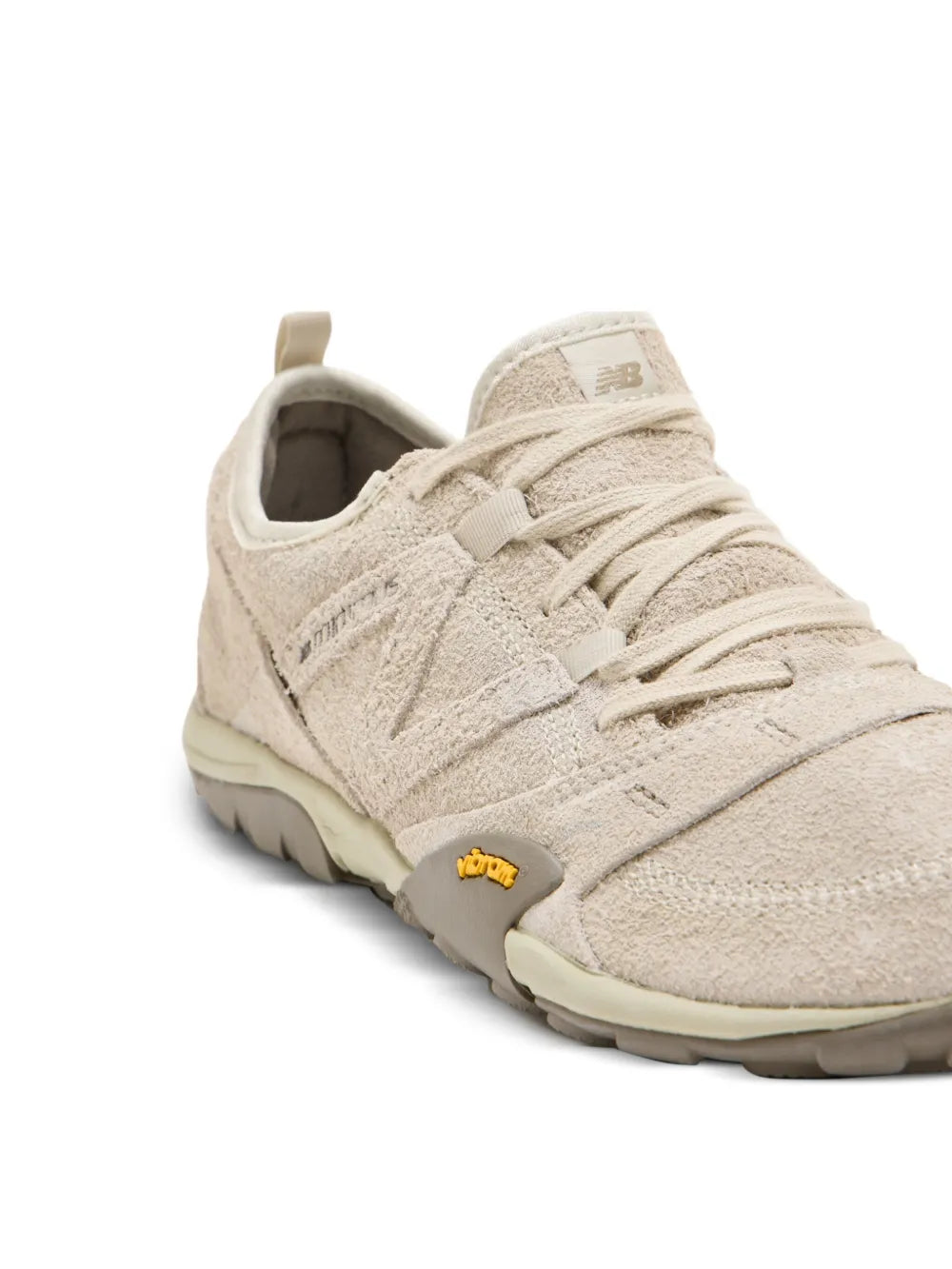 Beige New Balance suede lace-up sneaker upper detail with laces and logo patch