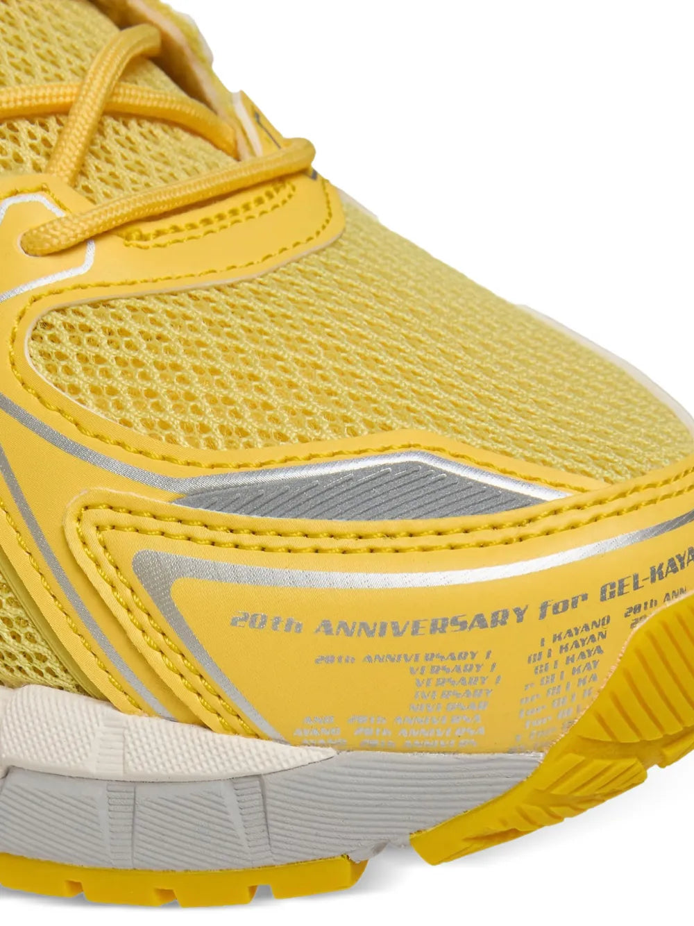 Yellow running shoe heel with strap, gray heel panel, and anniversary text branding