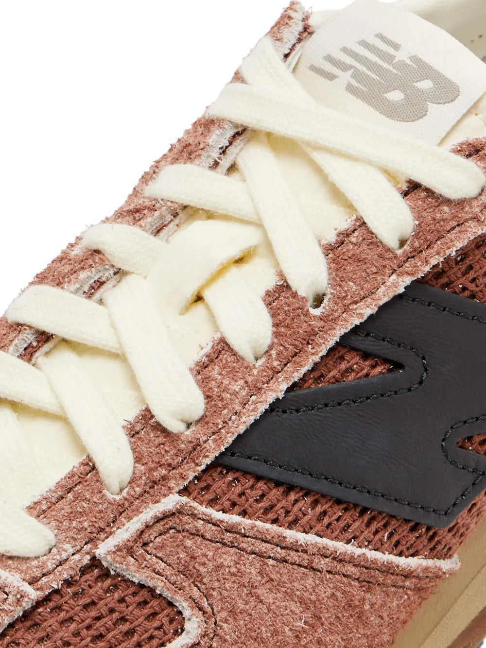 Brown suede sneaker close-up with off-white laces and black side panel