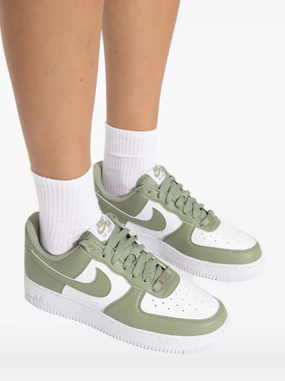 Green and white Nike lace-up sneakers worn with white crew socks