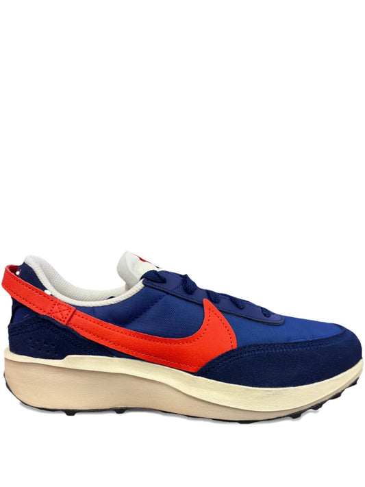 Blue Nike waffle running trainers with orange swoosh, white midsole, side view