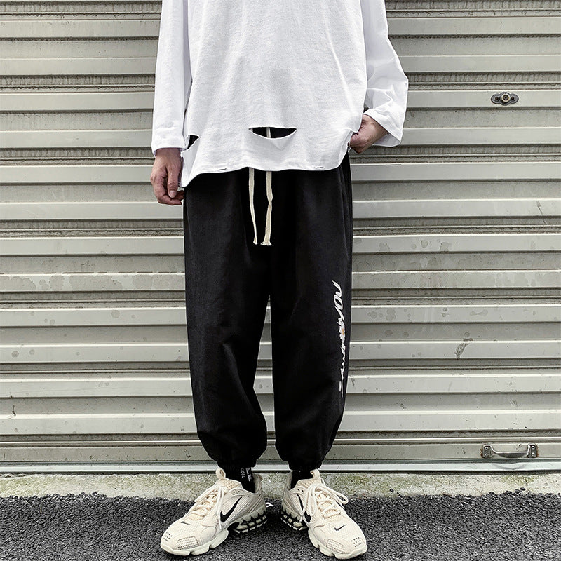 Black tapered jogger pants with elastic cuffs and white vertical side logo