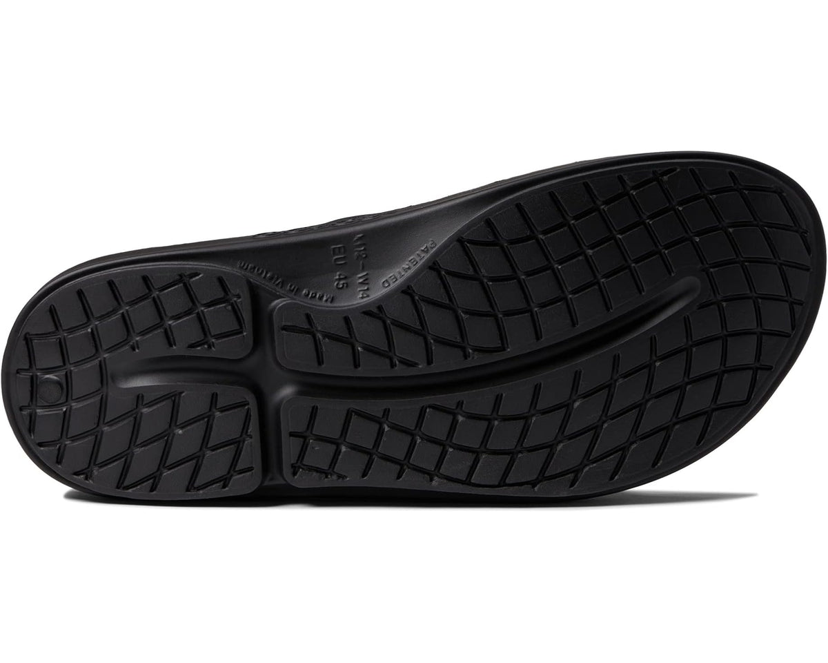 Black slide sandal outsole with textured tread pattern and logo