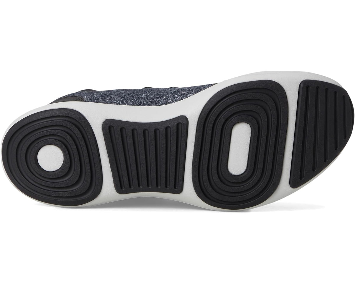 White rubber outsole with black circular and striped tread pattern on dark sneaker
