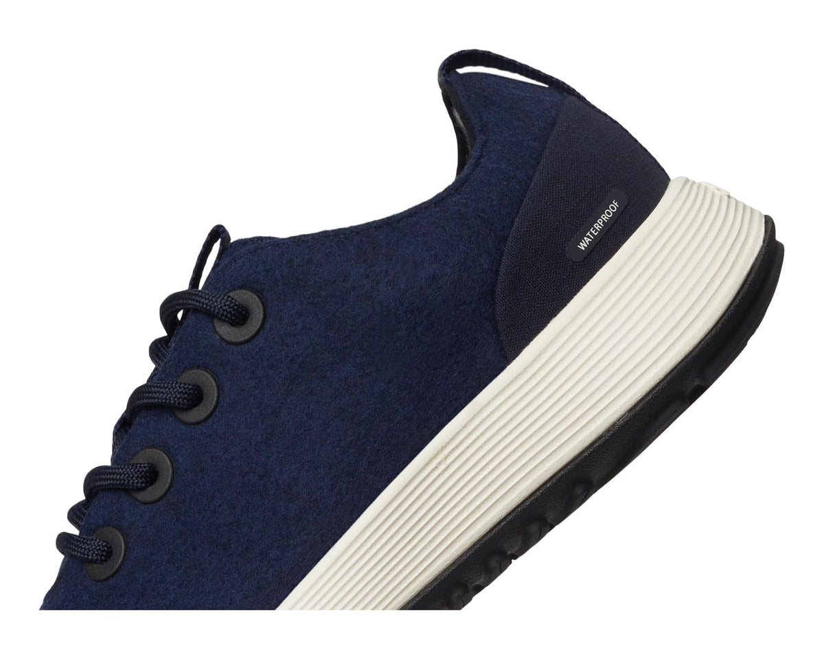 Navy sneaker with sock-like ankle opening, lace eyelets, and white striped midsole