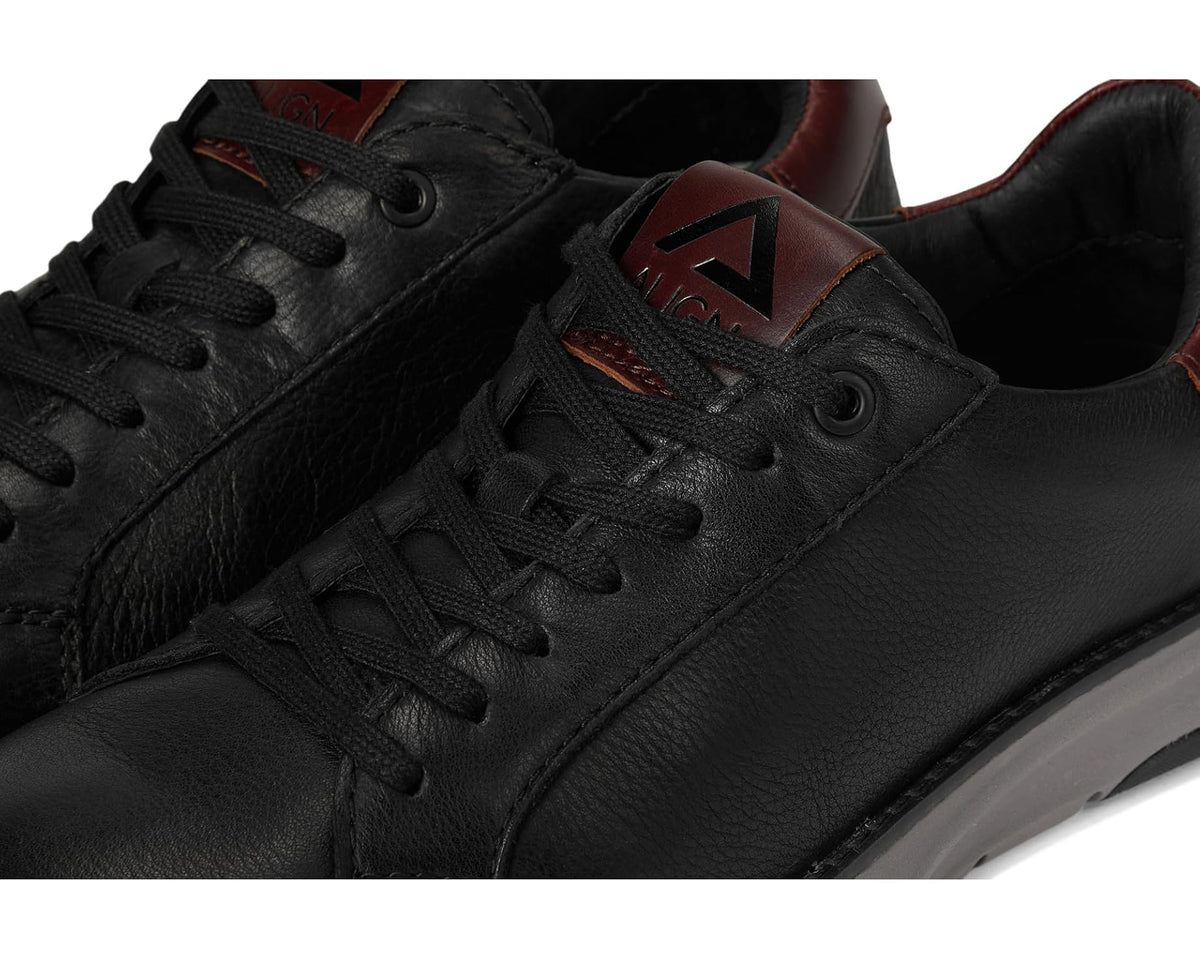Men's black leather sneaker close-up with lace eyelets and brown logo detail