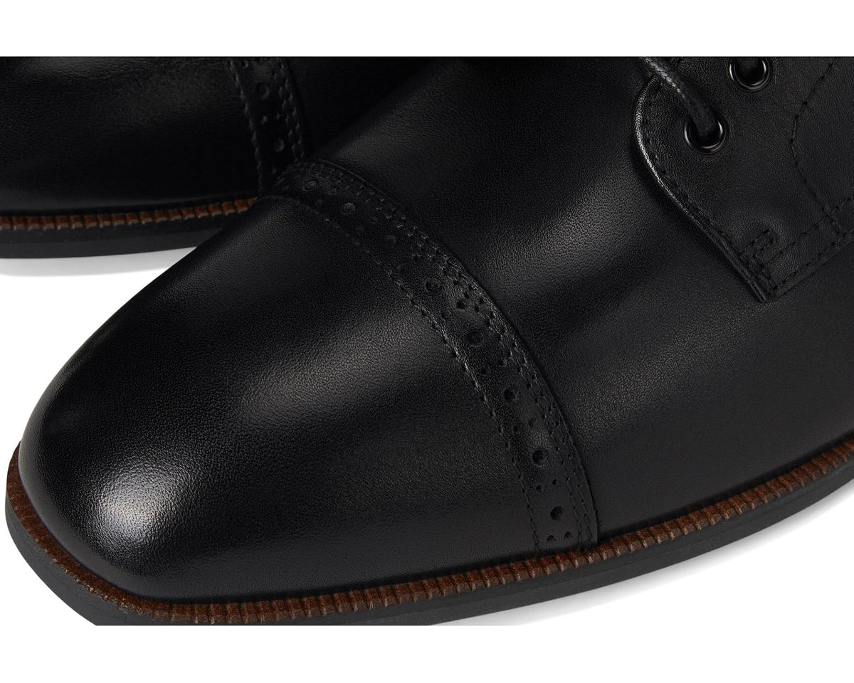 Close-up of black leather cap-toe with perforations and detailed stitching.