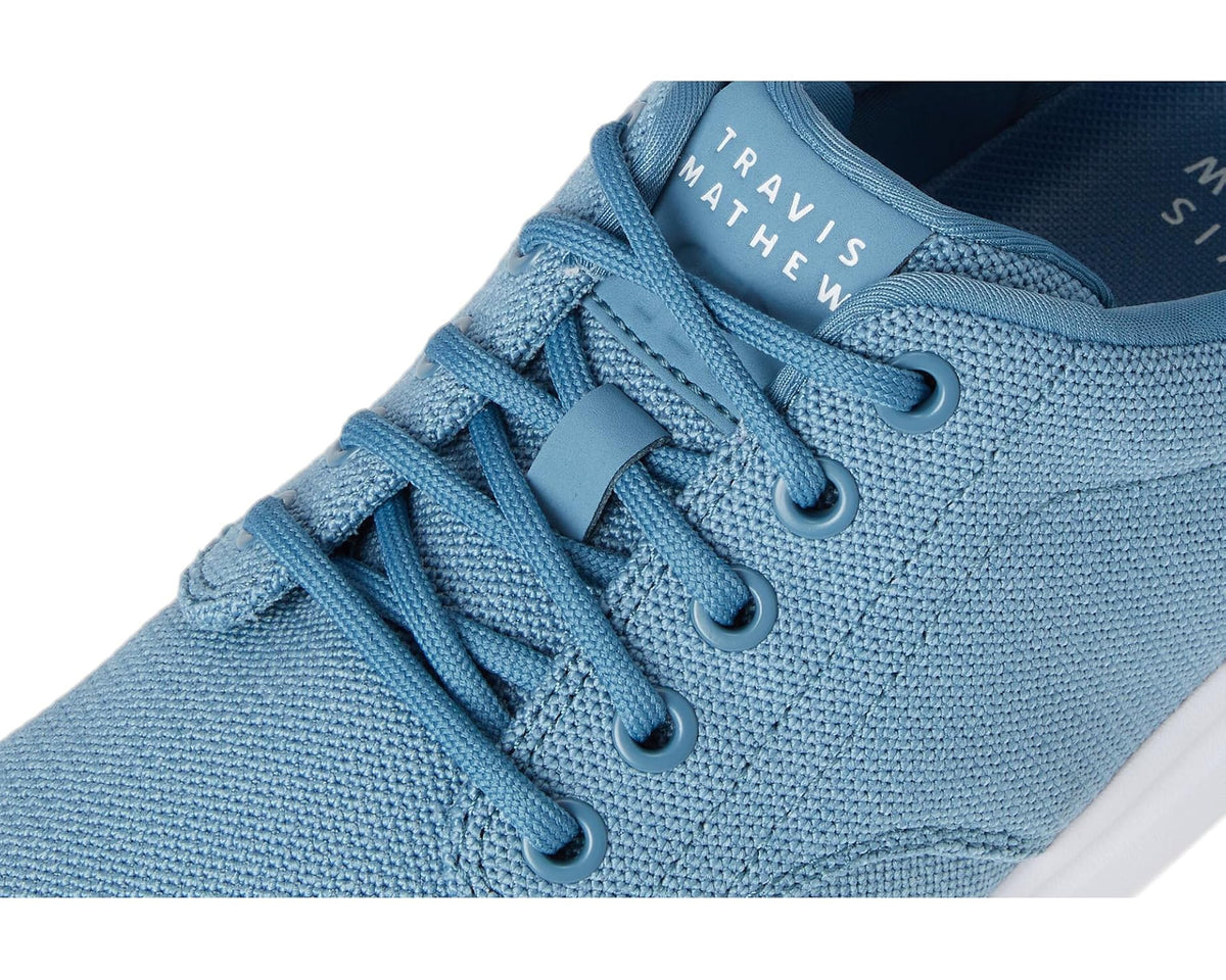 Men's blue knit sneaker close-up, lace-up eyelets and TravisMathew logo lining