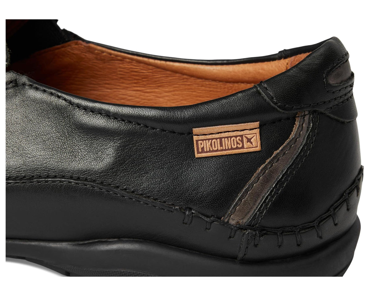 Men's black leather slip-on shoe close-up with PIKOLINOS logo patch on side