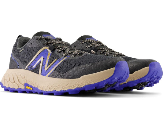 Men's New Balance trail running shoes in black with blue N logo, laces, purple outsole.