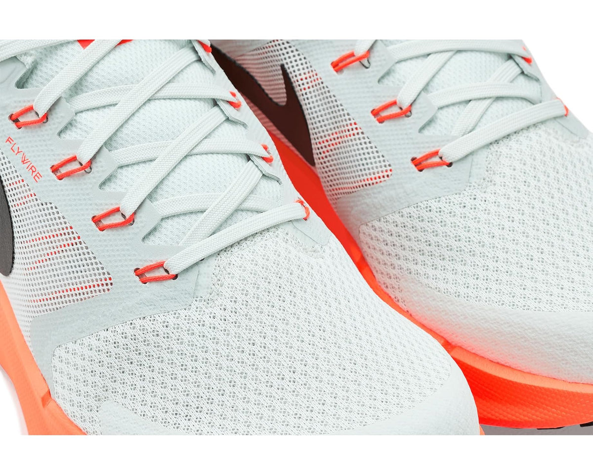 Men's Nike running shoes close-up: light gray knit, red lace accents, black logo.