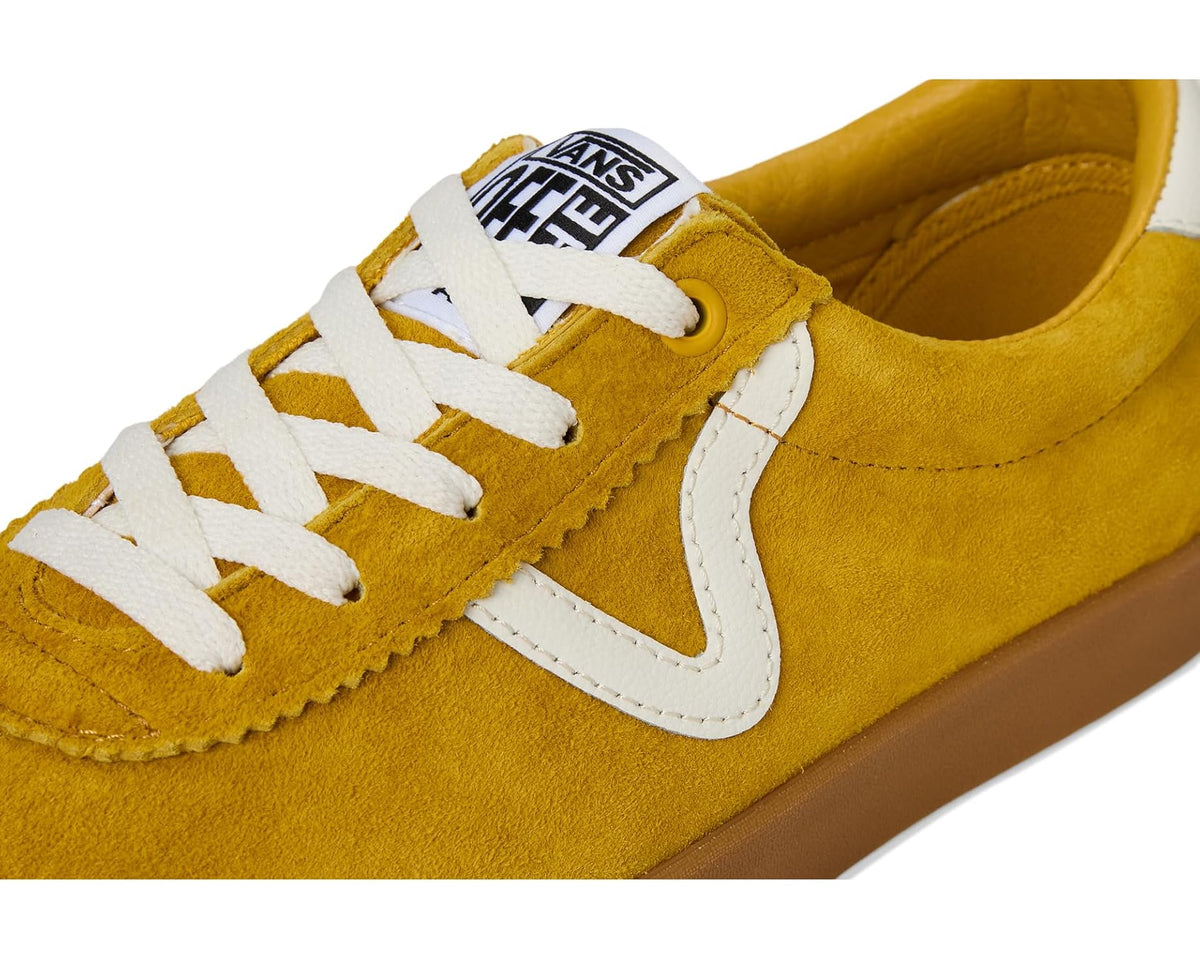 Close-up of mustard suede low-top sneaker with white laces and logo tongue