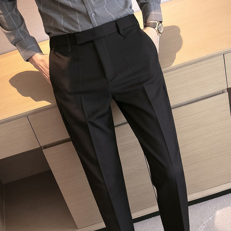 Men's black dress pants detail: pleats, belt loops, and straight trouser legs